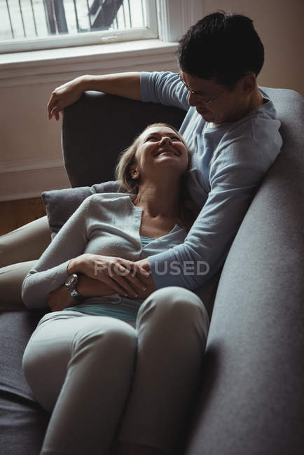 Casal romântico no sofá interagindo uns com os outros em casa — Fotografia de Stock