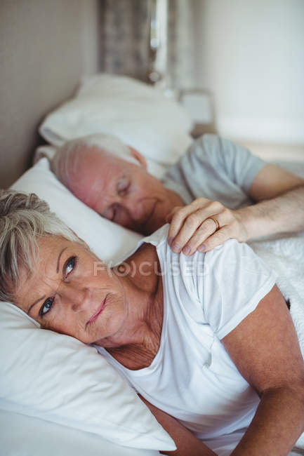 Старший пара, лежачи на ліжку в спальні — стокове фото