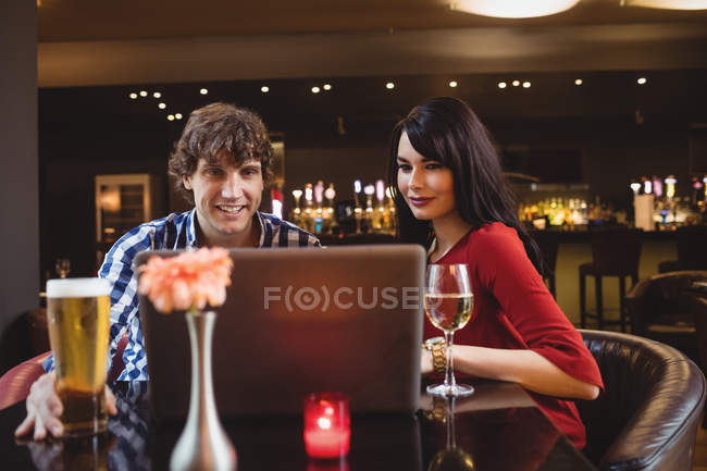 Пара використовує ноутбук під час напоїв у барі — стокове фото