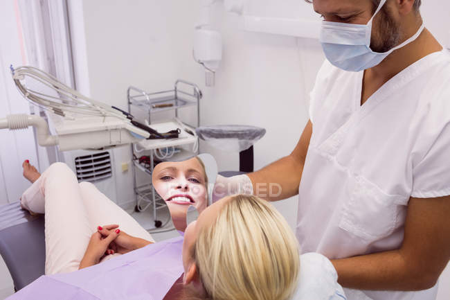 Dentista specchio davanti al volto del paziente in clinica — Foto stock