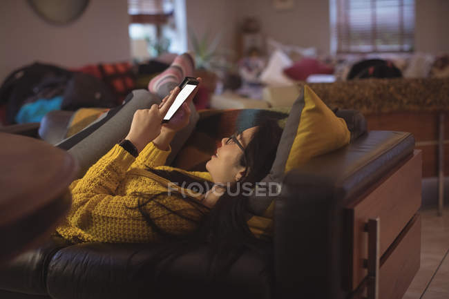 Mulher bonita mentindo e usando telefone celular em casa — Fotografia de Stock
