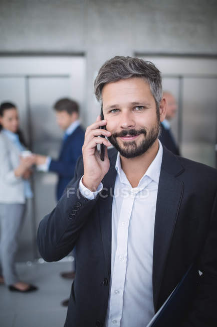 Uomo d'affari che parla al cellulare in ufficio — Foto stock