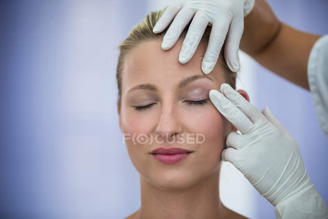 Руки лікар вивчення жіноче обличчя пацієнта для косметичне лікування — стокове фото