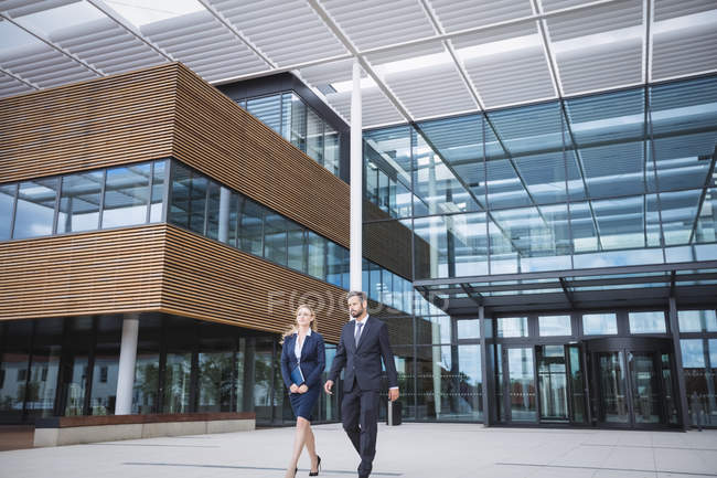 Geschäftsmann läuft mit Kollege vor dem Eingang eines Bürogebäudes — Stockfoto