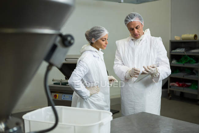 Carniceiros discutindo sobre prancheta na fábrica de carne — Fotografia de Stock