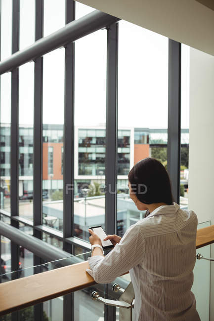 Rückansicht einer Geschäftsfrau mit Handy auf Bürobalkon — Stockfoto