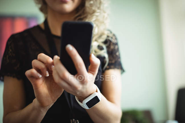 Деловая женщина с помощью мобильного телефона в офисе — стоковое фото