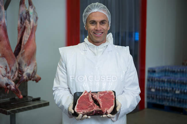 Portrait of butcher holding meat tray at meat factory — Stock Photo