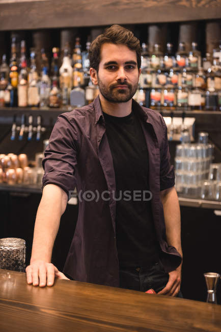 Ritratto di un barista sicuro in piedi al bancone del bar — Foto stock
