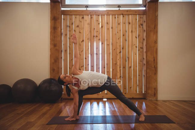Femme adulte moyenne pratiquant le yoga dans un studio de fitness — Photo de stock