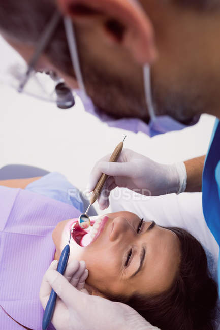 Стоматолог вивчає жіночого пацієнта з інструментами в стоматологічній клініці — стокове фото