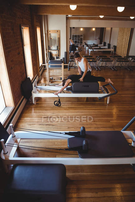 Coach assisting a woman while practicing pilates in fitness studio — Stock Photo