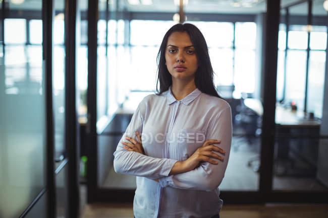Porträt einer Geschäftsfrau, die mit verschränkten Armen im Büro steht — Stockfoto