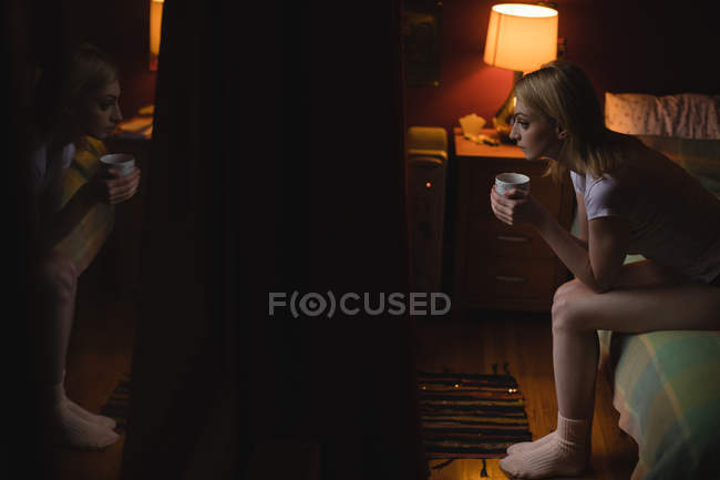 Женщина пьет кофе в спальне дома — стоковое фото