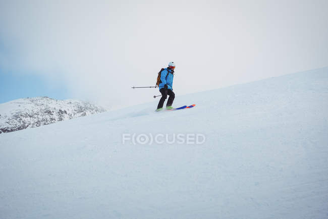 Esquiador esquiando en montañas cubiertas de nieve - foto de stock