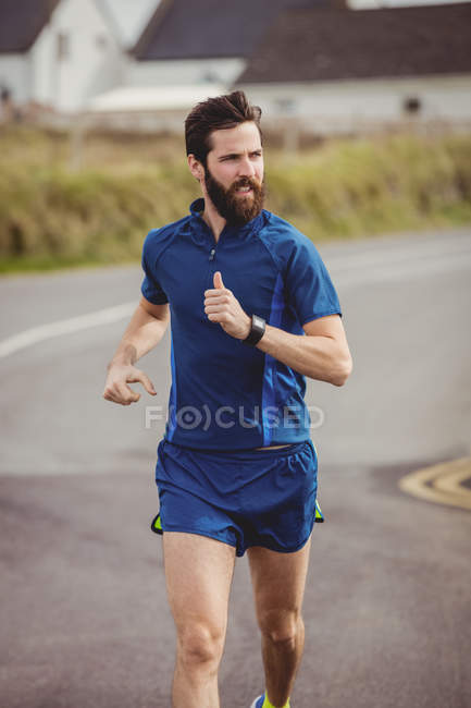 Handsome athlete running on the road — Stock Photo