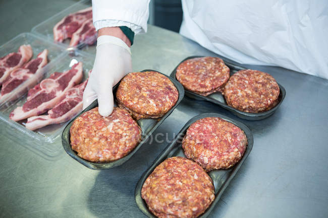 Sezione centrale del macellaio che organizza polpette su vassoio in fabbrica di carne — Foto stock