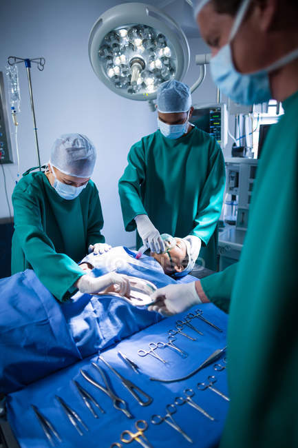 Grupo de cirujanos realizando operación en quirófano del hospital - foto de stock