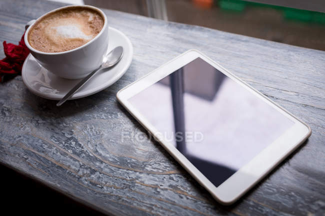 Cappuccino and digital tablet on table in cafe — Stock Photo