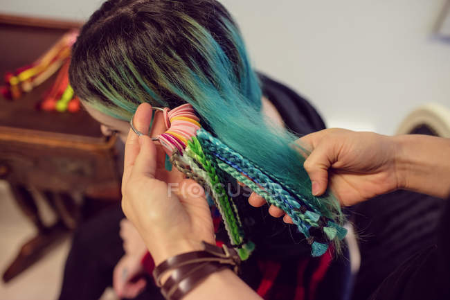 Female shop owner choosing dreadlocks for client in shop — Stock Photo