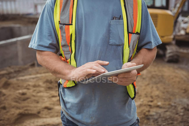 Средняя секция строителя с использованием цифрового планшета на строительной площадке — стоковое фото