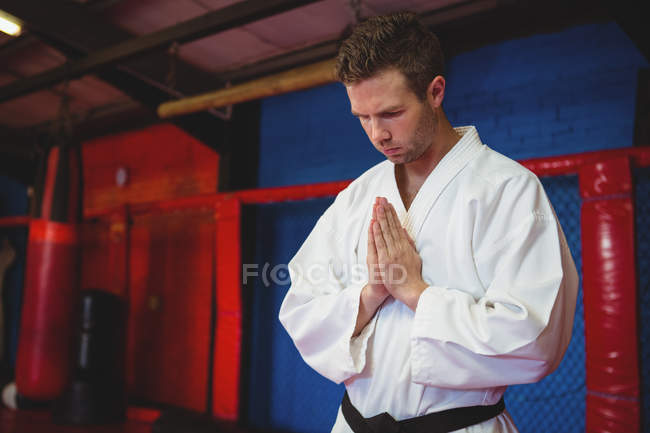 Giocatore di karate in posa di preghiera in palestra — Foto stock