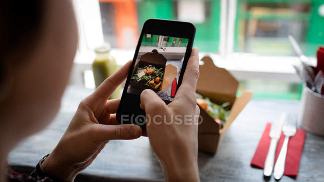 Mulher clicando em uma foto de salada de telefone celular no café — Fotografia de Stock