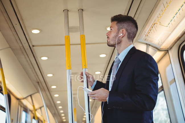 Empresário ouvindo música e usando no celular no trem — Fotografia de Stock