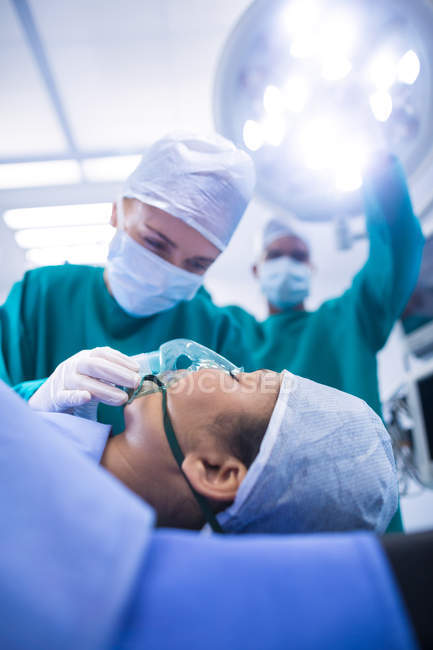 Cirujanos ajustando máscara de oxígeno en paciente en quirófano hospital — Joven, Inconsciente - Stock Photo |