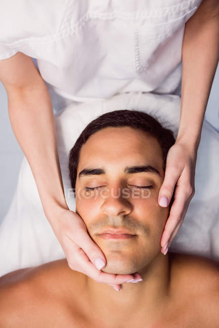 Man getting facial massage for cosmetic treatment at clinic — Stock Photo