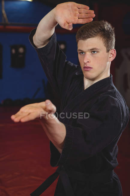 Jovem jogador de karatê adulto realizando postura de karatê no estúdio de fitness — Fotografia de Stock