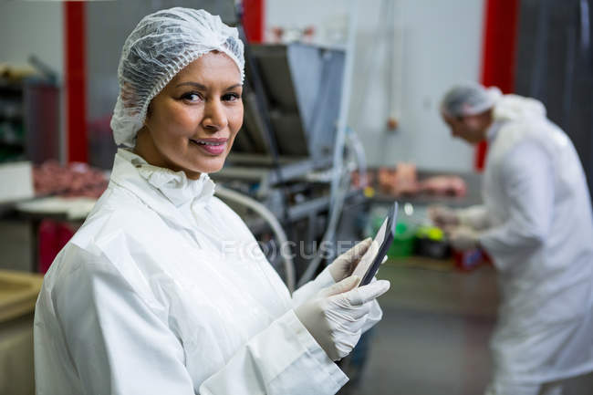 Retrato de açougueiro fêmea segurando tablet digital na fábrica de carne — Fotografia de Stock