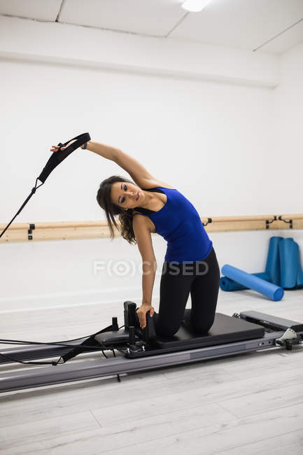 Femme faisant de l'exercice sur l'équipement de réformateur dans la salle de gym — Photo de stock