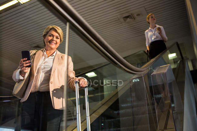 Portrait of female passenger coming down from the escalator in the airport terminal — Stock Photo