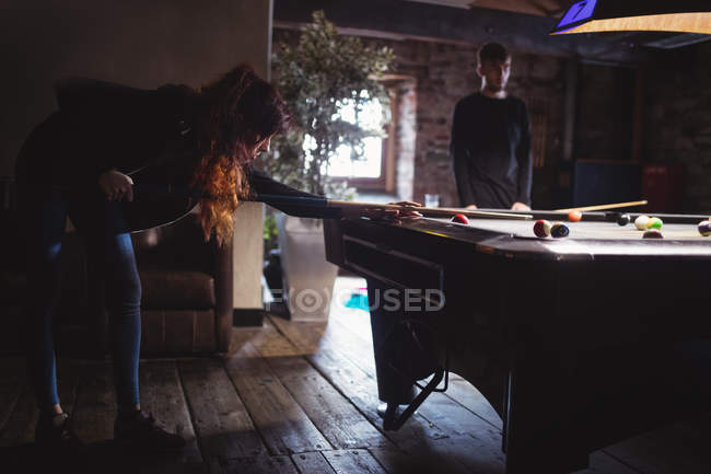 Jeune couple jouant au billard au bar — Photo de stock