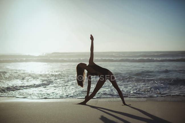 Mulher realizando ioga na praia ao entardecer — Fotografia de Stock