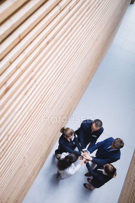 Overhead view of business people stacking hands together in office — Stock Photo
