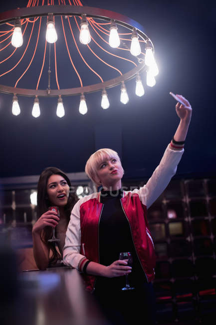 Amici sorridenti che prendono selfie mentre bevono vino nel bar — Foto stock