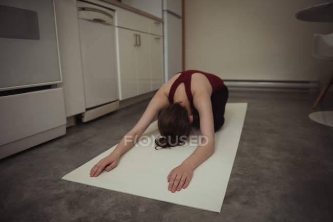 Mulher realizando ioga na cozinha em casa — Fotografia de Stock