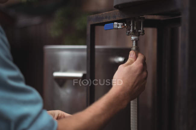 Close-up of man fixing pipe to beer wort to make beer at home brewery — Stock Photo