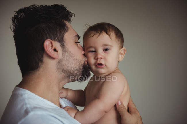 Pai beijando bonito bebê filho na bochecha — Fotografia de Stock