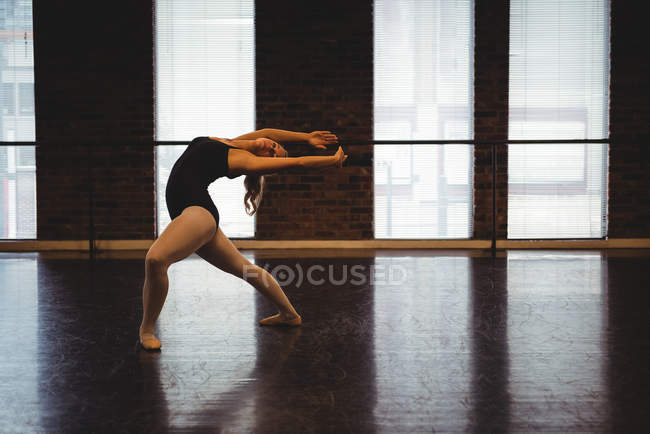 Bailarina realizando movimiento de baile de ballet en estudio de ballet - foto de stock