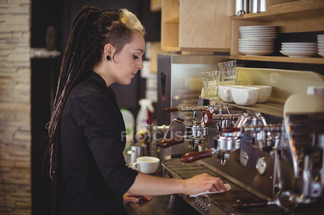 Camarera limpiando la máquina de café espresso con servilleta en la cafetería - foto de stock