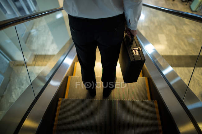 Sección baja del hombre en escaleras mecánicas en el aeropuerto - foto de stock