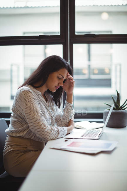 Стрессовая деловая женщина сидит за его столом в офисе — стоковое фото
