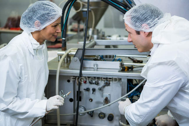 Técnicos examinando la máquina de procesamiento de carne en la fábrica de carne - foto de stock