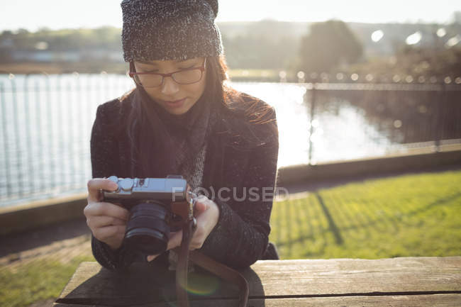 Mulher olhando para fotos na câmera digital em um dia ensolarado — Fotografia de Stock
