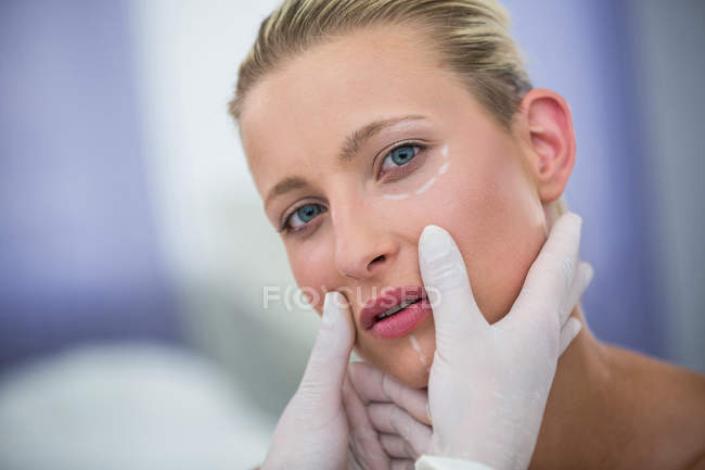 Medico esaminando volto paziente femminile per il trattamento cosmetico in clinica — Foto stock