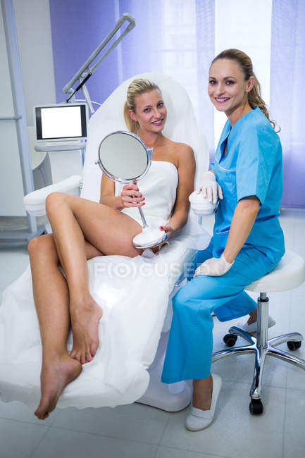 Dermatologa femminile e paziente che sorride alla macchina fotografica in clinica — Foto stock