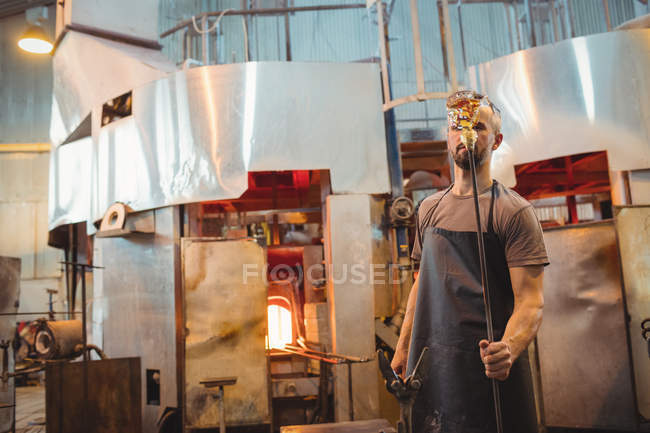 Стеклодув держит трубу на стеклодувном заводе — стоковое фото